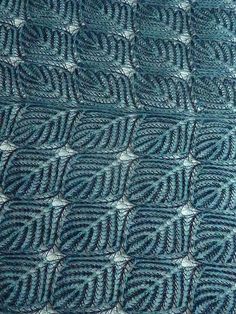 a blue knitted blanket with white stitchs