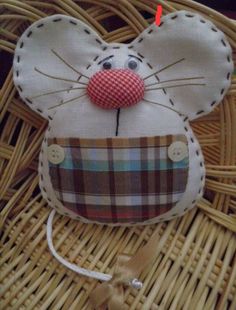 a mouse made out of fabric sitting on top of a wicker basket next to a string