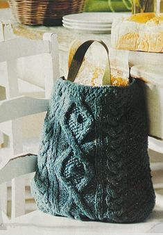 a knitted bag sitting on top of a wooden table next to a white chair