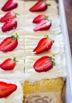 there is a cake with white frosting and strawberries on the icing sheet