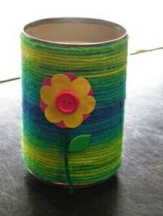 a tin can with a flower painted on it sitting on top of a wooden table