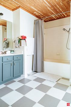 a bathroom with a checkered floor and blue cabinets, white walls and wood ceiling