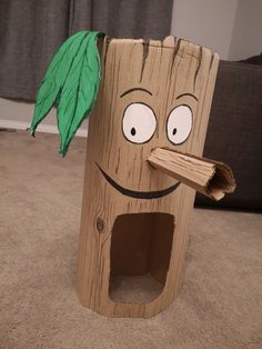 a cardboard tree stump with a green leaf sticking out of it's mouth and eyes