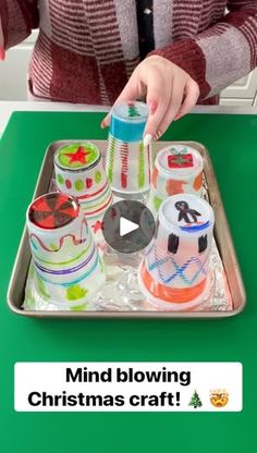 a woman is decorating christmas cupcakes on a tray with the words, mind blowing christmas craft?