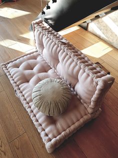 a couch that is on the floor with a pillow in it's back end