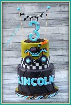 a three tiered cake with cars on it and the number 3 is made out of fondant