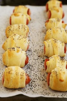 hotdogs wrapped in bread and sprinkled with poppy seeds on a baking sheet