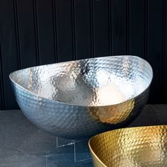 two large metal bowls sitting on top of a table