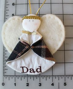 an angel ornament with the word dad on it and a ruler behind it