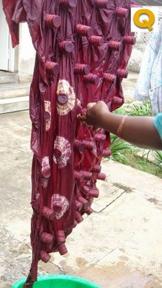 a woman is drying red onions on a clothes line