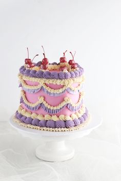 there is a cake that has cherries on top and purple icing with white ruffles