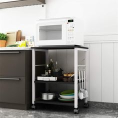 a microwave oven sitting on top of a shelf next to a kitchen counter with dishes and utensils