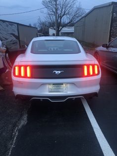 the rear end of a white mustang parked in a parking lot