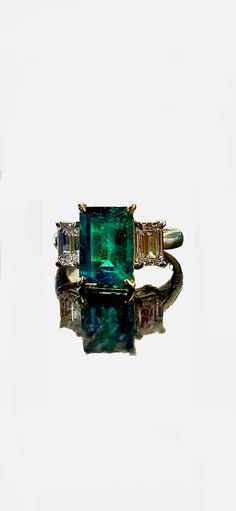 Dekara Designs Collection Metal- 90% Platinum, 10% Iridium. 18K Yellow Gold, .750. Stones- GIA Certified Colombian Emerald 2.92 Carats, 2 Emerald Cut Diamonds, E Color SI1 Clarity 0.75 Carats, E Color SI1 Clarity 0.71 Carats. Colombian Emerald Report Number 2211407292 E SI1 0.75 Carat Diamond Report Number 1363361525 E SI1 0.71 Carat Diamond Report Number 1368156510 Ring Comes With Three GIA Certificates. Beautiful Handmade Art Deco Inspired Ring Featuring an Elongated Colombian Emerald and Emerald Cut Diamond Three Stone Engagement Ring Handmade in Platinum and 18K Yellow Gold. The ring features a very fine beautifully cut and elegantly set amazing forest green emerald cut Colombian Emerald that is GIA Certified set in between four double pronged 18K Yellow Gold "Eagle Claws". The emerald Luxury Emerald Gemstones With Accent Stones, Luxury Three Stone Emerald Ring, Luxury Emerald Three Stone Ring For Formal Occasions, Luxury Three Stone Emerald Ring For Formal Occasions, Luxury Three Stone Emerald Ring For Formal Events, Luxury Emerald Ring With Baguette Cut And Accent Stones, Luxury Multi-stone Emerald Cut Emerald Ring, Luxury Three Stone Gemstones For Anniversary, Luxury Yellow Gold Gia Certified Gemstones