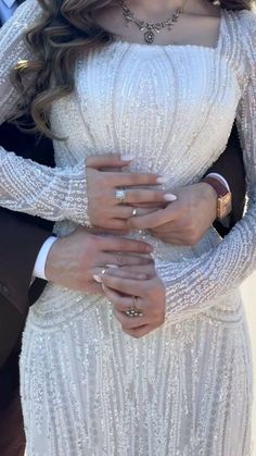 a man and woman in formal wear embracing each other with their hands on their chest