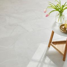 a vase with flowers and candles on a small table in the middle of a room