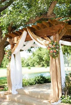 an outdoor gazebo with white drapes and flowers