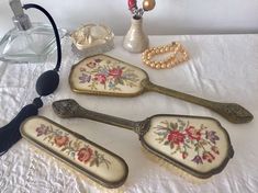 five antique spoons and two glass bottles on a white cloth covered tablecloth with beads