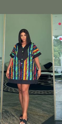 a woman standing in front of a mirror wearing a colorful shirt and black skirt with multicolored stripes on it