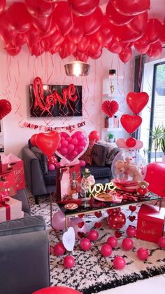 a living room filled with lots of red balloons and heart - shaped decorations on the ceiling