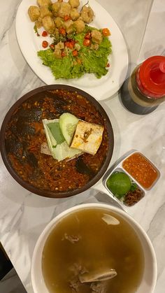 there are many different foods in bowls on the counter top, including soup and salad