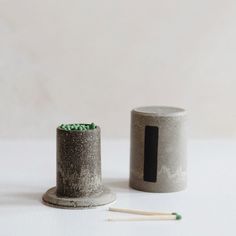 two concrete containers with matchesticks next to each other