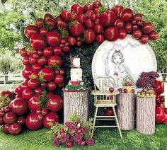 an apple themed dessert table with apples on the top and red flowers in the bottom