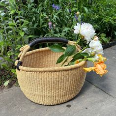 a basket with flowers in it sitting on the ground