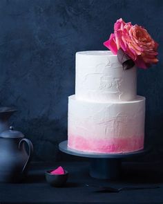 a white and pink cake sitting on top of a table next to a tea pot