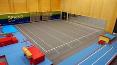 an indoor tennis court with blue and red benches on the sidelines in front of it