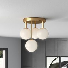 three lights are hanging from the ceiling in a room with gray walls and black cabinets