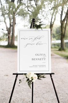 a welcome sign with flowers and greenery on it