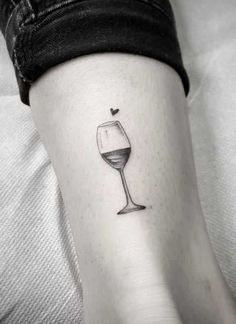 a woman's foot with a wine glass tattoo on her left leg and a heart in the middle