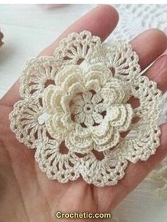 crocheted flower brooch in white color being held by someone's hand