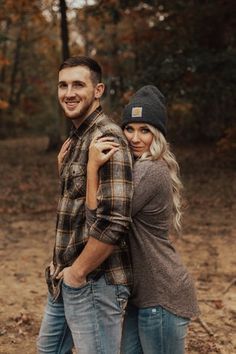 a man and woman are standing together in the woods with their arms around each other