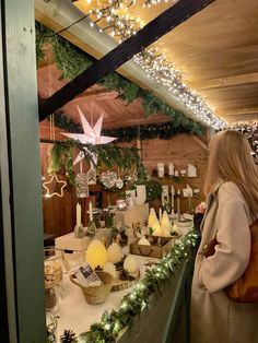 a woman standing in front of a counter with christmas decorations on the wall behind her