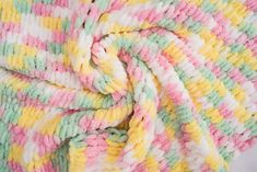 a multicolored crocheted blanket laying on top of a bed