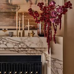 a marble fireplace mantel with candles and flowers on it in front of a painting