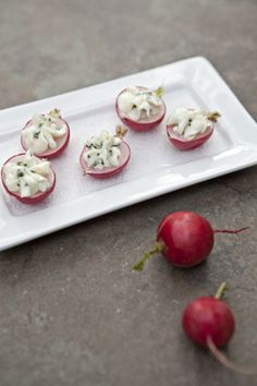 small appetizers are arranged on a plate with radishes next to them