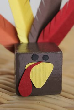 a wooden block with a turkey face and feathers sticking out of it's sides