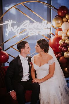 the bride and groom are sitting together in front of balloons