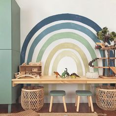 there is a table with two stools in front of it and a mural on the wall behind it