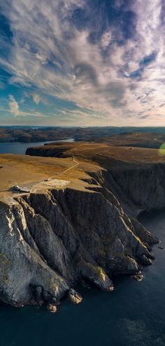 an aerial view of the ocean and mountains with clouds in the sky over it,