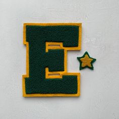 the letter e is made out of green and yellow felt with a star next to it