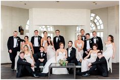 a large group of people in formal wear posing for a wedding photo with the bride and groom