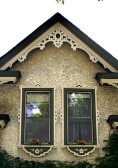 an old house with two windows that have flowers in them