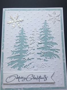 a christmas card with trees and snowflakes on the front, in blue and white