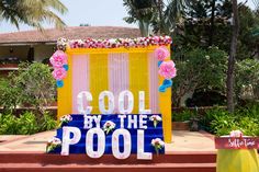 a sign that says cool by the pool in front of some flowers and plants on steps