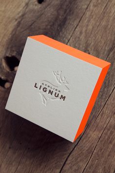 an orange and white business card sitting on top of a wooden table