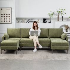 a woman sitting on top of a green couch with a laptop computer in her lap